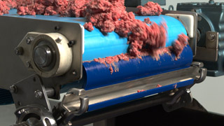 Ground beef being scraped off by conveyor belt cleaner